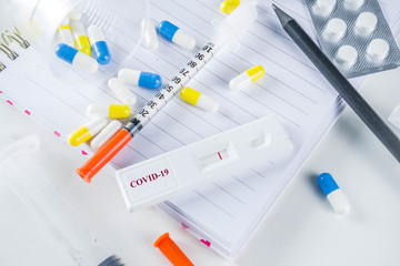 Worldwide coronavirus epidemic concept. Pandemic COVID-19, 2019-nCoV. Laboratory test strip for antibody or sars-cov-2 virus disease. In doctor hands. With pills, vaccination syringes, notebook.