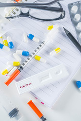 Worldwide coronavirus epidemic concept. Pandemic COVID-19, 2019-nCoV. Laboratory test strip for antibody or sars-cov-2 virus disease. In doctor hands. With pills, vaccination syringes, notebook.