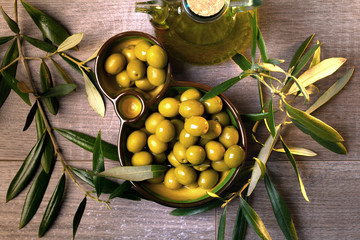 Aceitera con aceite de oliva virgen y aceitunas verdes frescas vista cenital