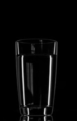glass of water on a black background. glare of light
