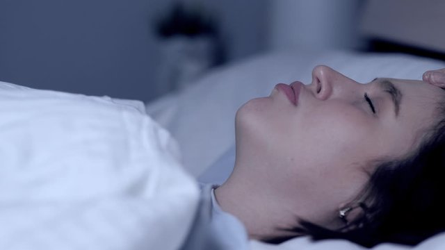 Girl snores. Stuffy nose, apnea, curvature of nasal septum, fatigue concept. Young attractive woman sleeps on her back in bed with open mouth. Close-up