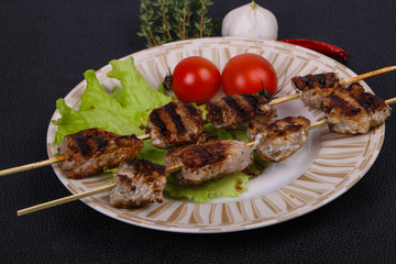 Pork kebab skewers in the plate with salad leaves and tomatoes