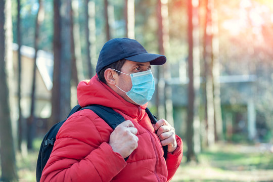 A Man In Medical Face Mask Outdoors. Man Traveler Walking In The Park