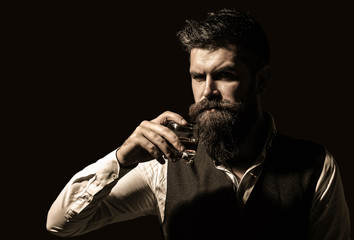 Man holding a glass of whisky. Sipping whiskey. Man with beard holds glass brandy. Macho drinking. Degustation, tasting. Bearded drink cognac. Sommelier tastes drink. Portrait of man with thick beard.