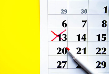 Numbers on the calendar crossed out with a red cross in macro on a yellow background. Calendar for plans, notes, meetings. Business calendar.  Marker for notes on the calendar. In the foreground.