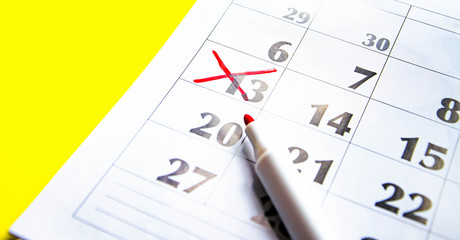 Numbers on the calendar crossed out with a red cross in macro on a yellow background. Calendar for plans, notes, meetings. Business calendar.  Marker for notes on the calendar. In the foreground.