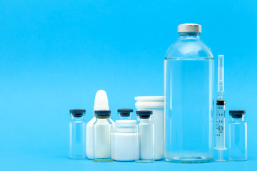 pharmaceuticals for the treatment of diseases unlable plastic and glass bottles with pills and vaccines on a blue background with copy space.