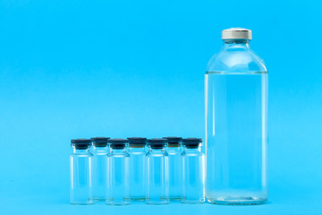 glass bottles with medicines for vaccines on a blue background on a medical theme with a copy space.