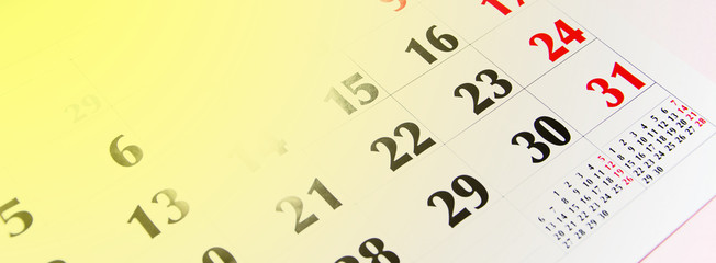 Macro calendar from different angles on a yellow and pink background. Black and red numbers on the calendar.  Copy Space