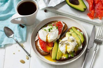 Morning breakfast. Poached egg boiled sandwich with avocado, salmon and coffee on a wooden table. Copy space.