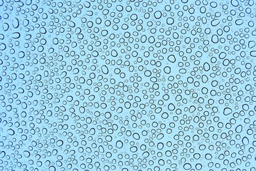 Abstract view of large rainwater drops on a glass window with blue background