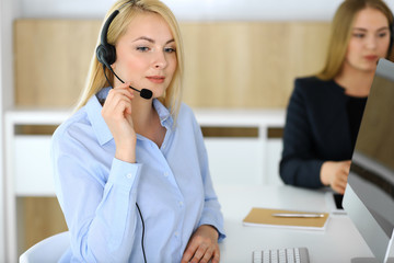 Call center. Blonde business woman sitting in headset at customer service office. Concept of telesales business or home office occupation