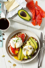 Morning breakfast. Poached egg boiled sandwich with avocado, salmon and coffee on a wooden table. Top view flat lay background.