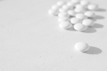 Fototapeta na wymiar a lot of white round tablets lying on a white background. side view