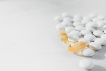 a lot of white round tablets and a few yellow capsules lying on a white background. the view from the top