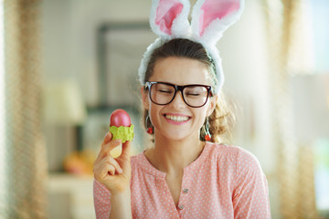 smiling modern housewife with glasses holding easter egg