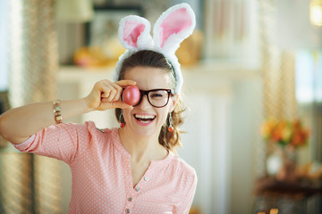 happy young woman with glasses showing red easter egg