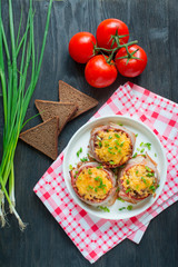 Baked minced meat wrapped in bacon on top of cheese and fresh herbs. View from above. Dark wooden background. Food background.