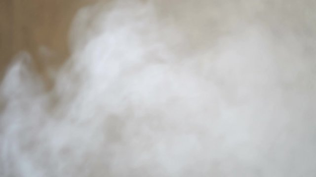 White steam on a gray wall background. Humidifier in the room. Inhaler for treatment. Close-up. Cloud of smoke.