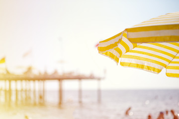 there is a large yellow-white striped umbrella on the beach