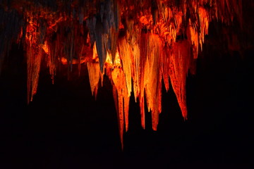 Limestone f stalactite formation that looks chandelier, Carlsbad Carven New Mexico, color of red with black background