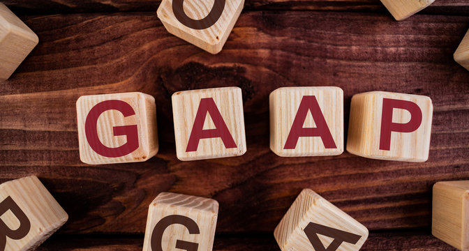 GAAP (Generally Accepted Accounting Practice) word on wooden cubes on a dark wood background. Business Concept image.