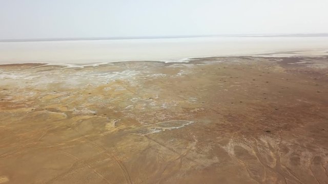 Panoramic top view of the Maranjob desert.The drone is approaching the salt lake Namak. Visible salt, wheel marks and traces of camels on sand