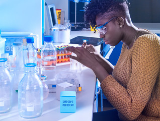 African female scientist, medical or graduate student in casual wear works in modern laboratory...