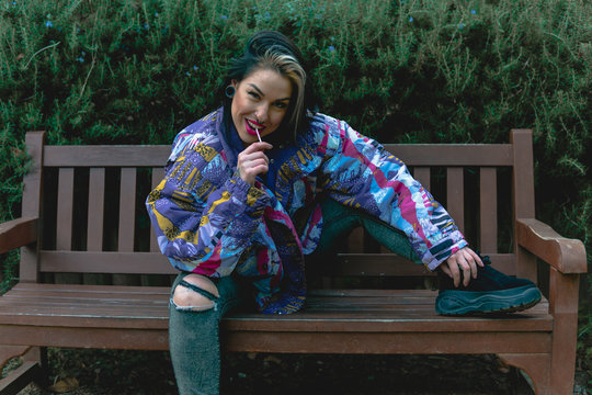 Chica chupando un caramelo sentada en un banco