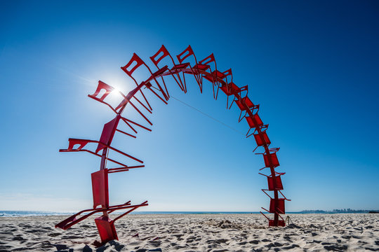 Red chairs in the air at the beach.