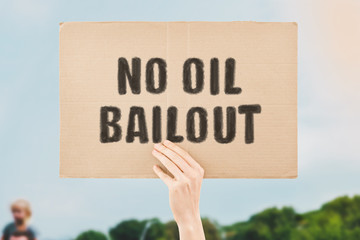 The phrase " No oil bailout " on a banner in men's hand. Human holds a cardboard with an inscription. Mineral resources. Energy. Environment. Business. Pollution. Finance. Economy. Economic. Subsoil