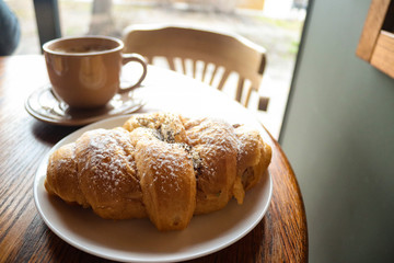 Food and drink concept. Croissant with cup of coffee on wooden table. Delicious French breakfast. Tasty food.