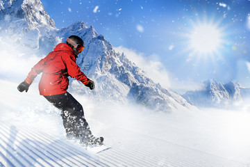 Fototapeta na wymiar Fast snowboarder riding on slope during beautiful sunny and snowy day in the alpine mountains.