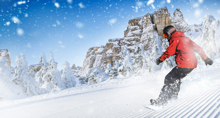 Fast snowboarder riding on slope during beautiful sunny and snowy day in the alpine mountains.