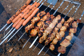 Preparation of shish kebab and sausages on outdoor charcoal grill