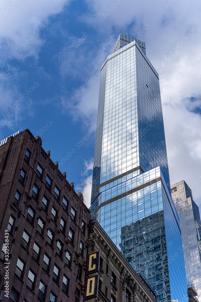 Wall mural reflections of the clouds on a glass skyscraper in new york city, scenic view from below