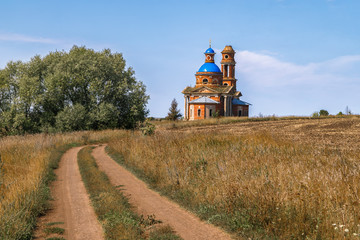 Fototapeta premium Abandoned church in the field (built in 1822), empty dirt road. Russia, Lipetsk region.