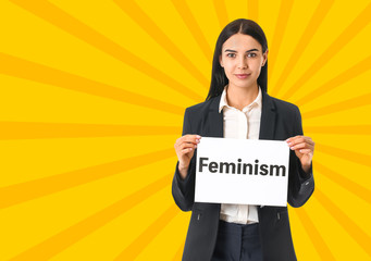 Young businesswoman holding paper with text FEMINISM on white background
