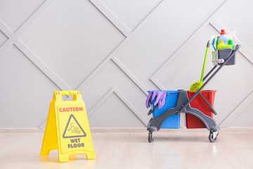 Caution sign with cleaning supplies indoors