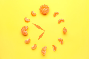 Creative clock made of fresh tangerines on color background