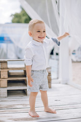 Little boy with blond hair in white clothes on the beach