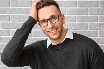 Portrait of handsome young man on grey brick background