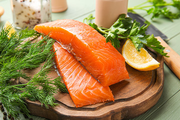 Raw salmon fillet with herbs and lemon on table