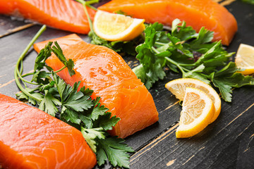 Raw salmon fillet with herbs and lemon on table