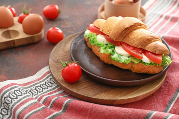 Tasty croissant sandwich on table