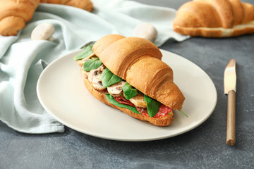 Tasty croissant sandwich on dark background