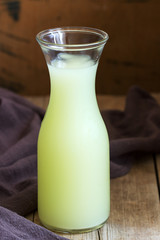 Chilled whey in a glass bottle on a wooden background.