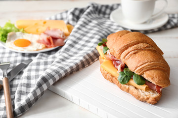 Tasty croissant sandwich on table