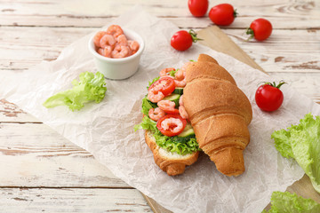 Tasty croissant sandwich on wooden table