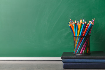 Set of school supplies on table near blackboard